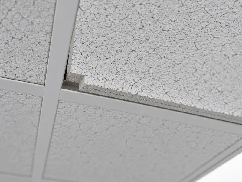 Close view of tegular-edge mineral fibre ceiling tiles sitting in a white exposed grid