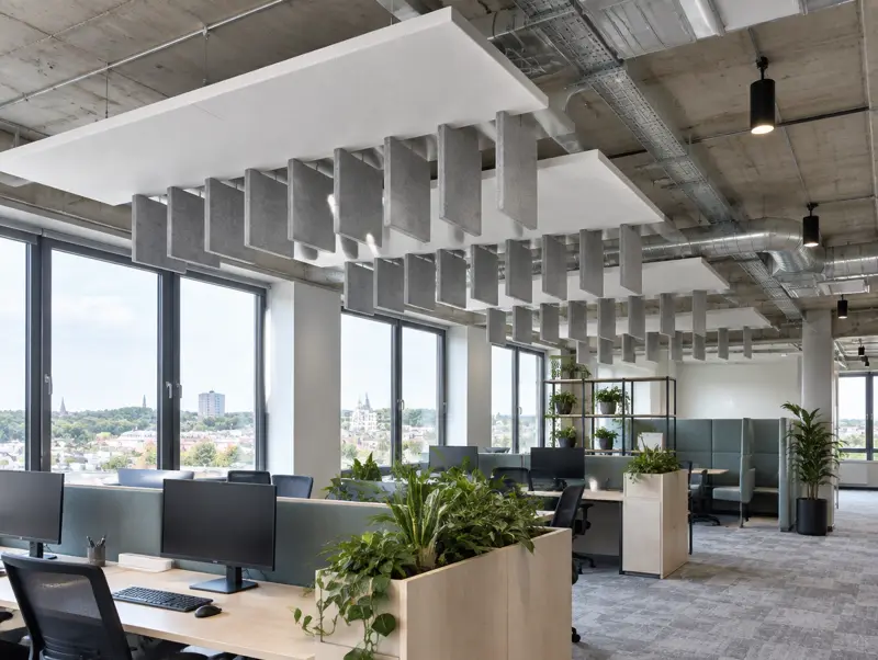 Open-plan office with suspended acoustic rafts and baffles below an exposed concrete soffit